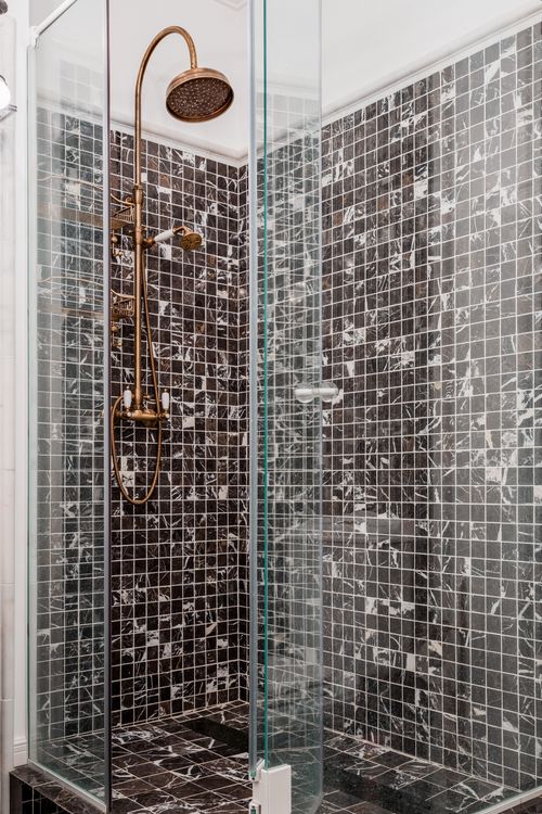 Modern shower cabin with stylish fixtures and mosaic tile